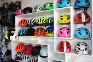 Eine große Auswahl an Fahrradhelmen in bunten Farben wird in einem Regal präsentiert.