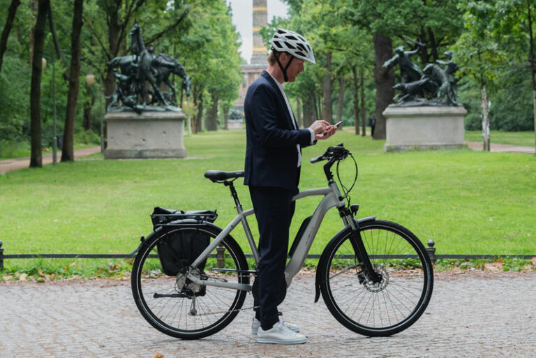 Ein Mann mit Fahrrad schaut auf sein Smartphone