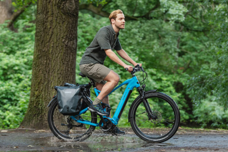 Ein Mann fährt mit einem türkisblauen Fahrrad durch eine Pfütze